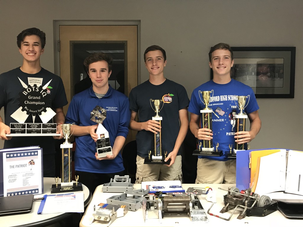 Nathaniel Semanek, Seth Montgomery, Luke Dague, and Lance Dague display their awards from the 2017-2018 Technology Student Association and Bots IQ season. The battle robot, located on the center of the table, is a fifteen-pound fighting machine that won Grand Champion at the SWPA Bots IQ competition. (l-r) Nathaniel Semanek, Seth Montgomery, Luke Dague and Lance Dague.